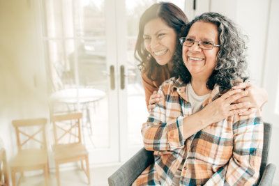 Two women. One has her arms around the other showing she cares